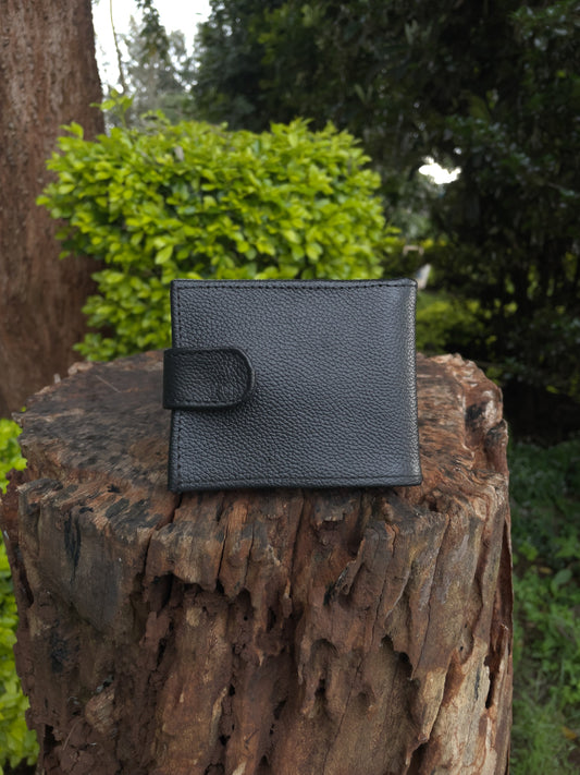 Black leather wallet on a wooden log with greenery in the background