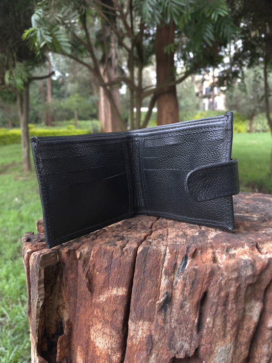 Black leather wallet leaning against a wooden log with a natural outdoor background